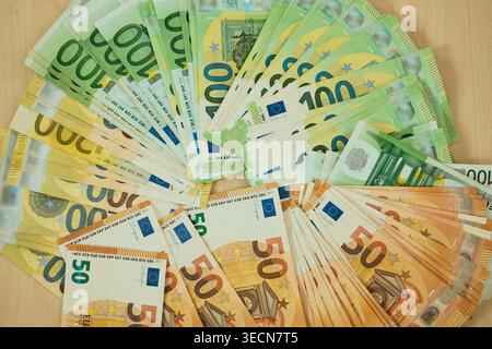 Euro banknotes are arranged in grouped stacks by denomination on a wooden surface. Cash savings and wealth concept for finance, budgeting, investment Stock Photo