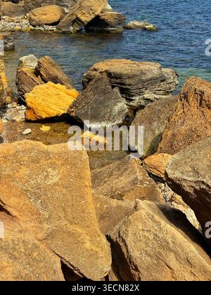 Close-up of massive yellow and brown sandstone rocks on a rocky beach. Stock Photo