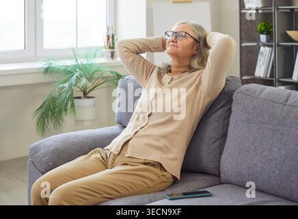 Happy Senior Woman Relaxing On Sofa At Home Stock Photo
