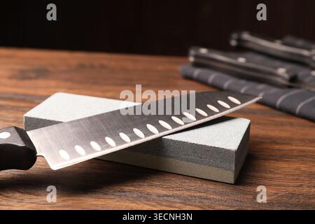 Sharpened knife and whetstone on wooden table. Space for text Stock Photo