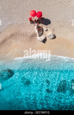 Aerial view of red umbrellas on white empty sandy beach, blue sea Stock Photo