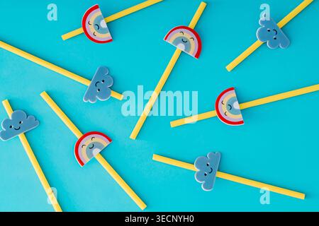 Cute rainbow and cloud drinking straws pattern on pastel blue background. Playful flat lay design. Top view. Stock Photo
