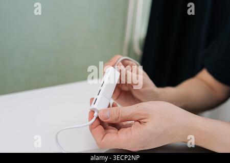 Hands holding white USB hub with multiple ports, poised to connect devices for expanded data transfer, charging and connectivity in clean modern Stock Photo