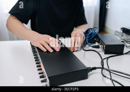 Close-up of hands plugging blue audio jack into sound mixer. Represents music production, sound engineering, or podcasting in studio setting with Stock Photo