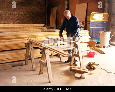 White male senior volunteer at Habitat for Humanity's Restore, measuring lumber, New Orleans, LA.  MR Stock Photo