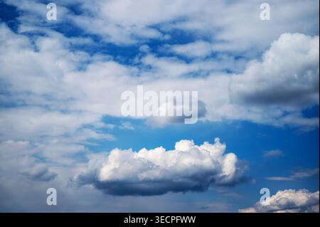 Fluffy white clouds floating across deep blue sky Stock Photo