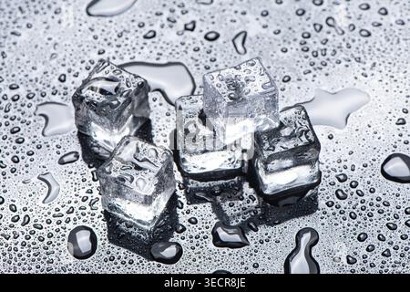 Ice cubes melting, creating water drops on a chilled metallic surface Stock Photo