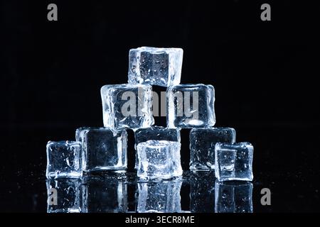 Ice cubes melting on a reflective surface, creating refreshment concept Stock Photo