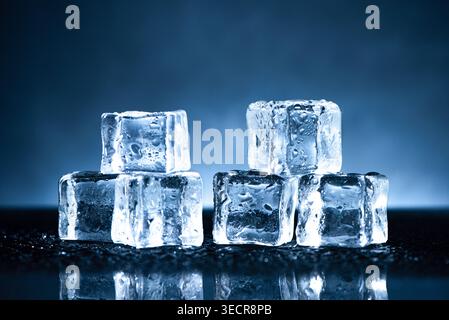 Ice cubes melting on a reflective surface, showing coldness and refreshment Stock Photo