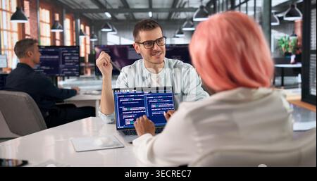Programmer Collaborates With Diverse Team Coding Software In Modern Office. Stock Photo