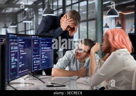 Software Engineer Struggles With Broken Code While Stressed At Desk. Stock Photo