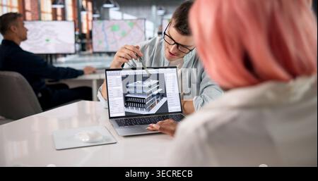 Architect Leads Diverse Team Reviewing 3D BIM Model During Project Meeting. Stock Photo