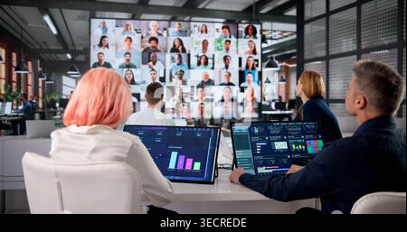 Executives Collaborate In Modern Boardroom Reviewing Financial Dashboard Data Together. Stock Photo