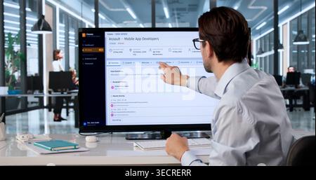 Experienced Police Officer Uses Touchscreen Computer To Review Criminal Case Files And Evidence. Stock Photo