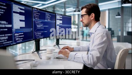 Mature Man Focused On Coding Software At Desk In Modern Office. Stock Photo