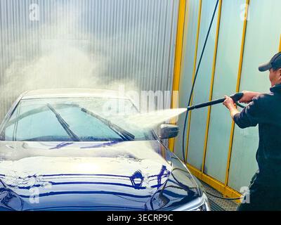 A man washes a car at a self-service car wash. Car wash concept Stock Photo