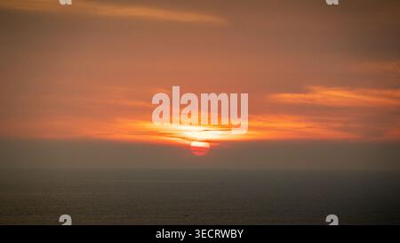 Captivating sunset with vibrant colors illuminating the sky and reflecting on the ocean. The sun sets slowly, casting a warm glow during the golden ho Stock Photo