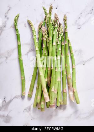 Top view of fresh green asparagus spears arranged on a clean white marble surface. Healthy spring vegetable ingredient for cooking, meal prep, and veg Stock Photo