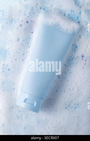 Minimal blue cosmetic cream tube mockup lying on white bubbly foam background, clean skincare concept for cleanser, moisturizer, packaging design, and Stock Photo
