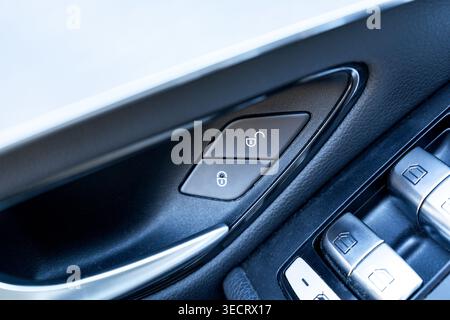 Detailed close-up of a modern car interior door panel showing lock and unlock buttons and power window controls, highlighting automotive design, safet Stock Photo