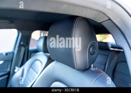Close-up view of a luxury car interior featuring a black leather headrest with stitching, soft focus cabin background, and premium upholstery textures Stock Photo