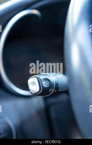 Close-up view of a car steering wheel area showing the windshield wiper and washer control stalk with icons, inside a modern vehicle interior in soft Stock Photo