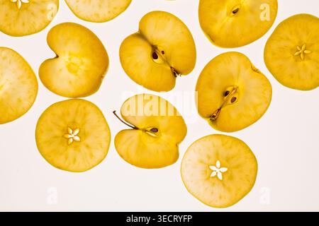 Flat lay pattern of golden apple slices and halved pieces on a clean light background, showing seeds and texture, ideal for food, healthy eating, and Stock Photo