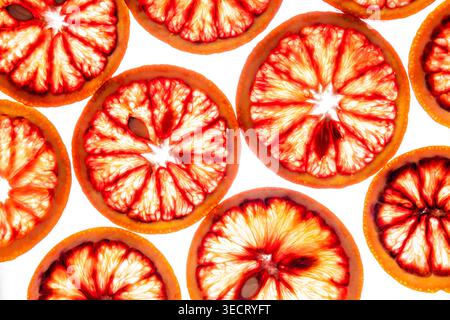Vibrant blood orange slices arranged in a seamless pattern on a clean white background, showing juicy red citrus segments and fresh texture in bright Stock Photo