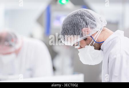 Close-up of a factory technician in a candy laboratory, wearing hairnet, mask and lab coat, focused on quality control in a clean, modern confectioner Stock Photo