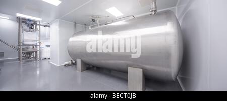 Large stainless steel storage tank in a clean candy laboratory factory, with sterile white walls, industrial piping, and bright lighting for food-grad Stock Photo