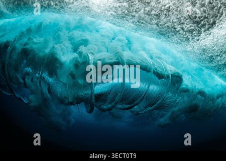 Dramatic underwater view of a powerful ocean wave curling overhead, with turquoise water, bubbles, and swirling foam, capturing energy, motion, and se Stock Photo