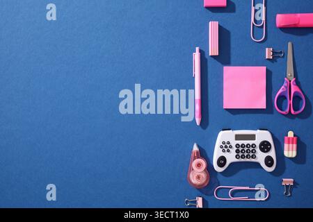 Pop art back to school flat lay on blue background with pink supplies and a gamification twist: a gamepad styled as a calculator, for Gen Z learning a Stock Photo