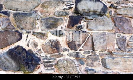 Exterior stone brick wall angled shape medieval Dark grey texture and background Stock Photo