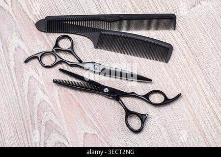 Professional barber instruments including scissors, thinning shears, and combs on wooden background Stock Photo