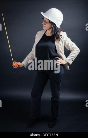 Woman engineer wearing hard hat holding measuring tape Stock Photo