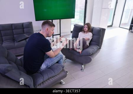 Engaging conversation between a man and a girl in a modern living room setting Stock Photo