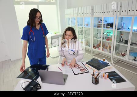 Two medical professionals collaborate on patient care in a bright clinic setting with advanced equipment Stock Photo