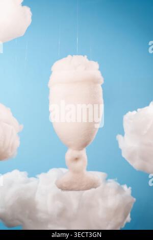 Floating goblet of fluffy white clouds against clear blue sky. Soft texture suggests gentle, dreamlike atmosphere. Ideal for whimsical, serene, or ima Stock Photo