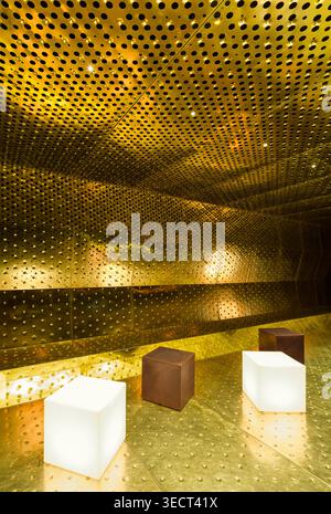 Luxurious nightclub interior with perforated gold panels and cube seats, creating a modern and elegant disco atmosphere, accentuated by ambient lighti Stock Photo
