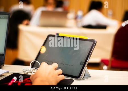 An engineer using a digital tablet with a stylus to view ETABS structural design data during a computer-aided civil engineering class in Bangkok. Stock Photo