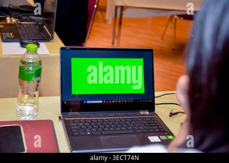 An engineer at a computer workstation looking at a green chroma key mockup screen window on a laptop during an engineering software class in Bangkok. Stock Photo
