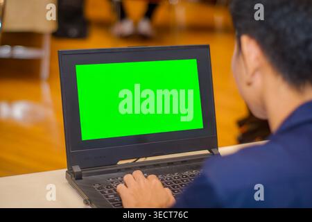 An engineer typing on a laptop computer displaying a green chroma key mockup screen window during a structural design software class in Bangkok. Stock Photo