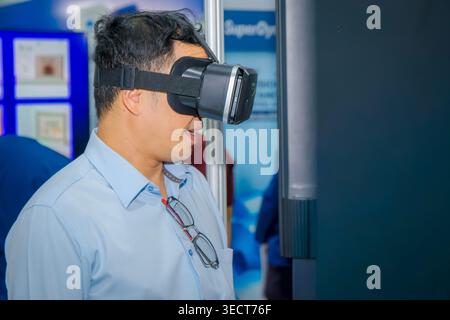 Asian Man Using VR Headset at Technology Expo - Immersive Virtual Reality Experience Stock Photo