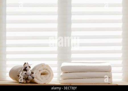 White bed linens sheets bedding and a terry towel with a cotton branch against the background of the window. Copy space. Stock Photo
