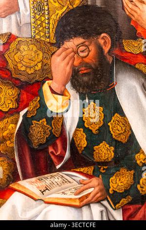 Detail of renaissance painting portraiting a mature bearded man using glasses to read the bible Stock Photo