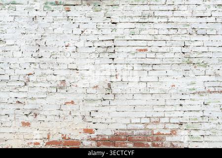 Close up of very old brick wall with cracked white peeling paint texture Stock Photo