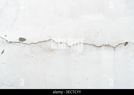 Close up of old white plaster wall with large crack and peeling texture Stock Photo