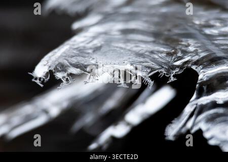 Macro profile of a crystalline overhang where thin spires dangle like ornaments. The water underneath blurs into darkness highlighting the sharp rim Stock Photo