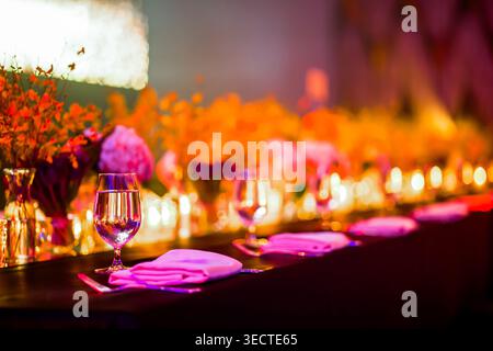 Elegant gala dinner table setting with pink and orange flowers at a luxury wedding reception venue. Stock Photo