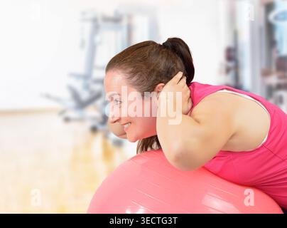 Shot of an attractive young woman working out with an exercise ball at gym Stock Photo